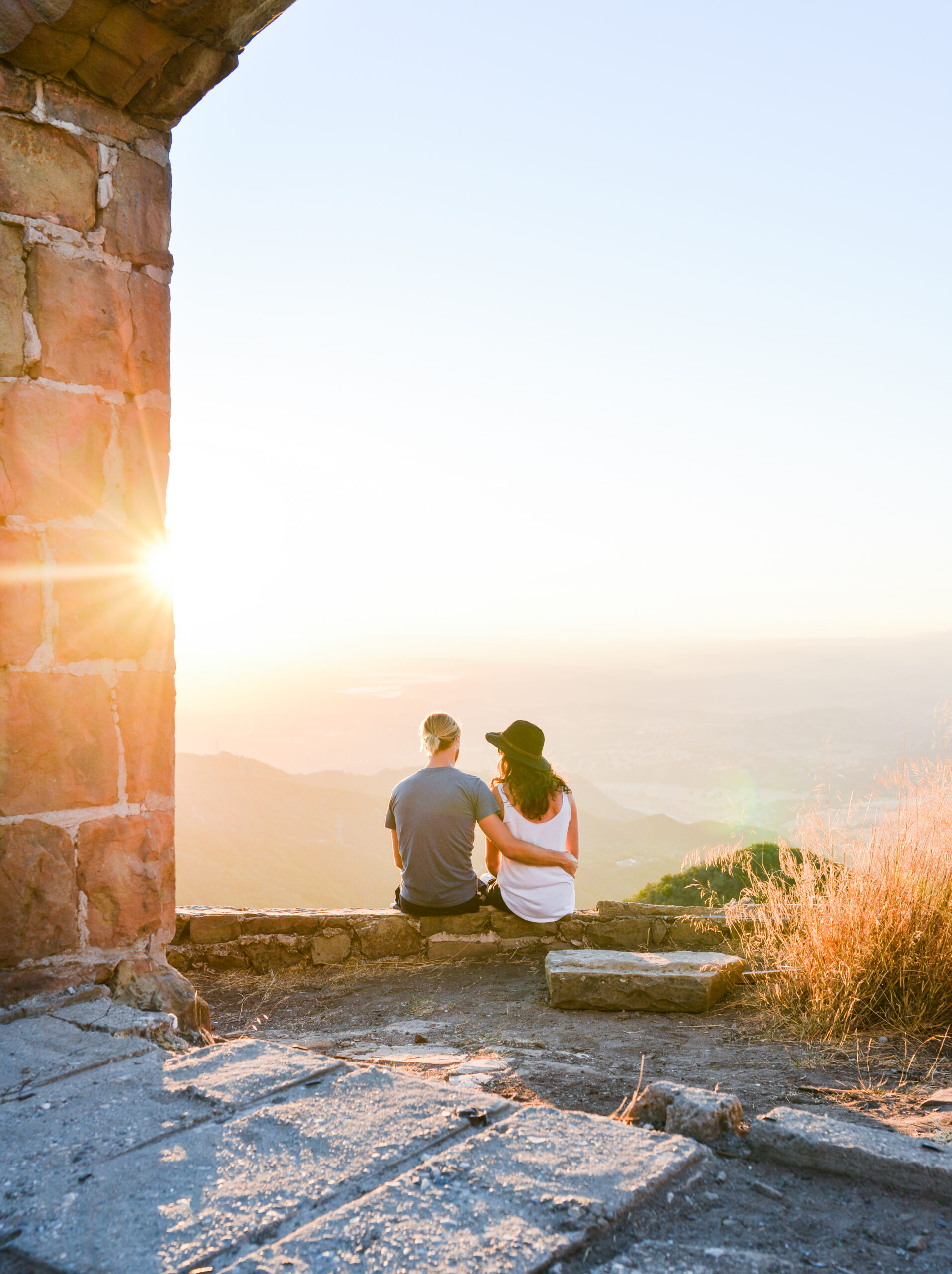 couple sitting on wall watching the sunset