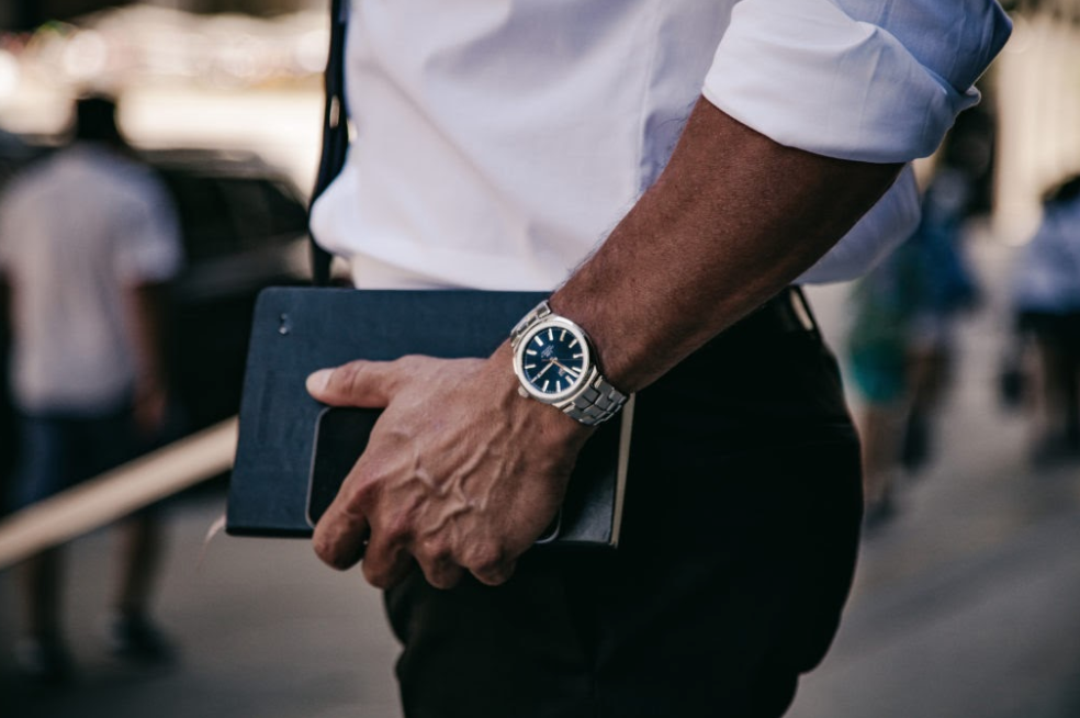 man holding phone and book with tag heuer watch on